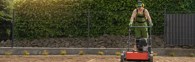 A Naco employee uses a lawnmower to landscape a building lot.