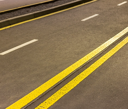 Freshly painted yellow lines on a roadway.