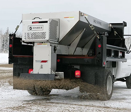 A de-icing truck sprays sand across an icy parking lot.
