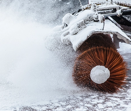 A snow plow brushes snow away from a parking lot after a snow fall.