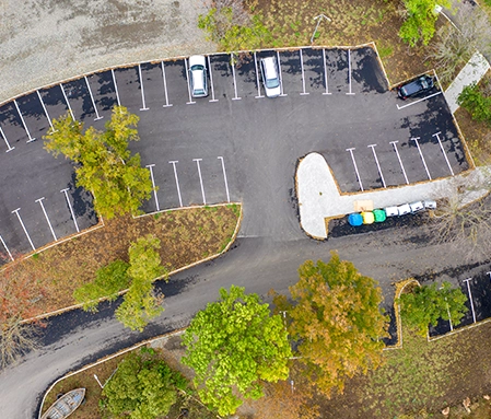 An aerial view of a clean parking lot bordered by neatly landscaped areas of trees.